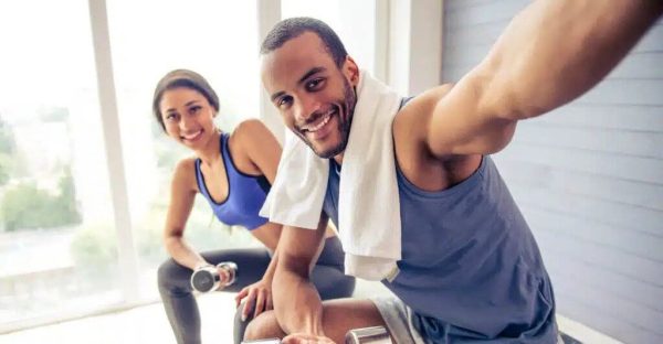 A man and woman smile while sitting together inside the gym, enjoying each other's company.