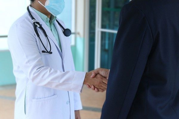 Two doctors shaking hands in an office, symbolizing collaboration and professionalism in a healthcare setting.