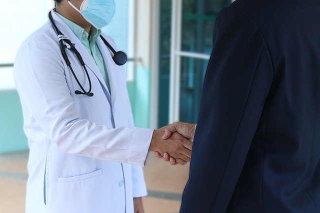Two doctors shaking hands in an office, symbolizing collaboration and professionalism in a healthcare setting.