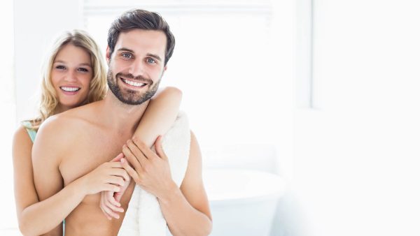 A couple shares a warm hug in a bathroom, conveying intimacy and connection.
